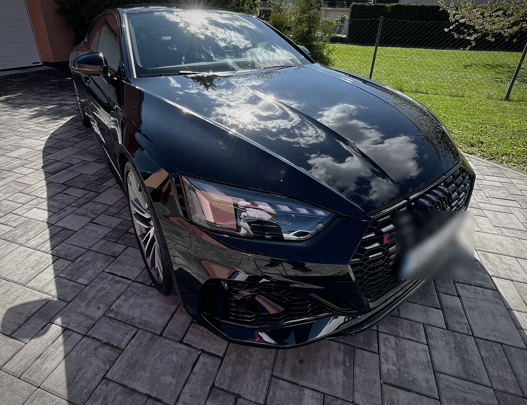 Predná časť čierneho Audi s odrazom oblohy v lesklom laku